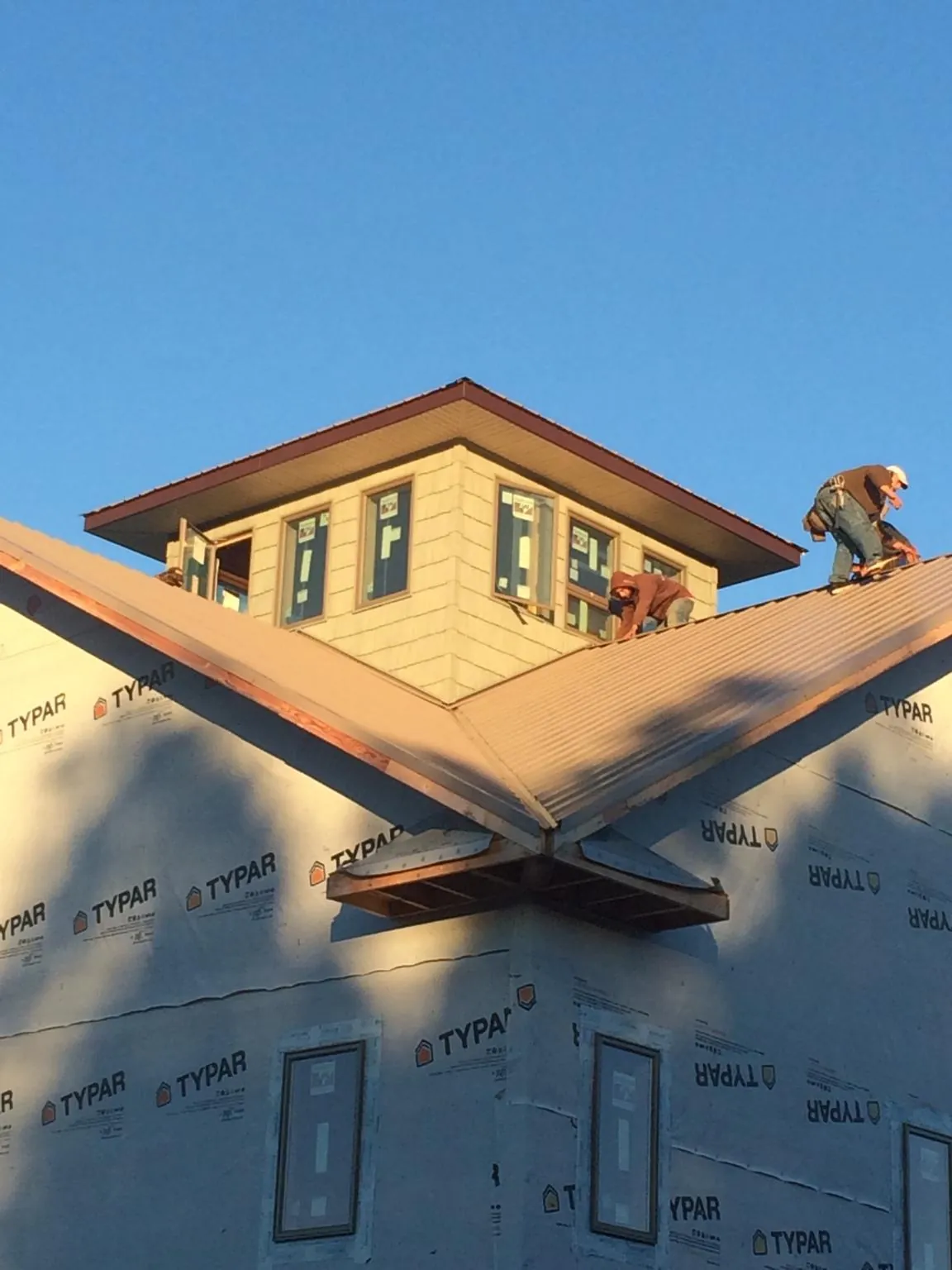 Roofers working around a rooftop cupola on a new metal roof at sunset — Roof Waterproofing in Howard by Roofing Brothers